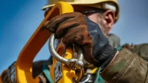 Closeup of a hand wearing safety gloves hanging onto a chain